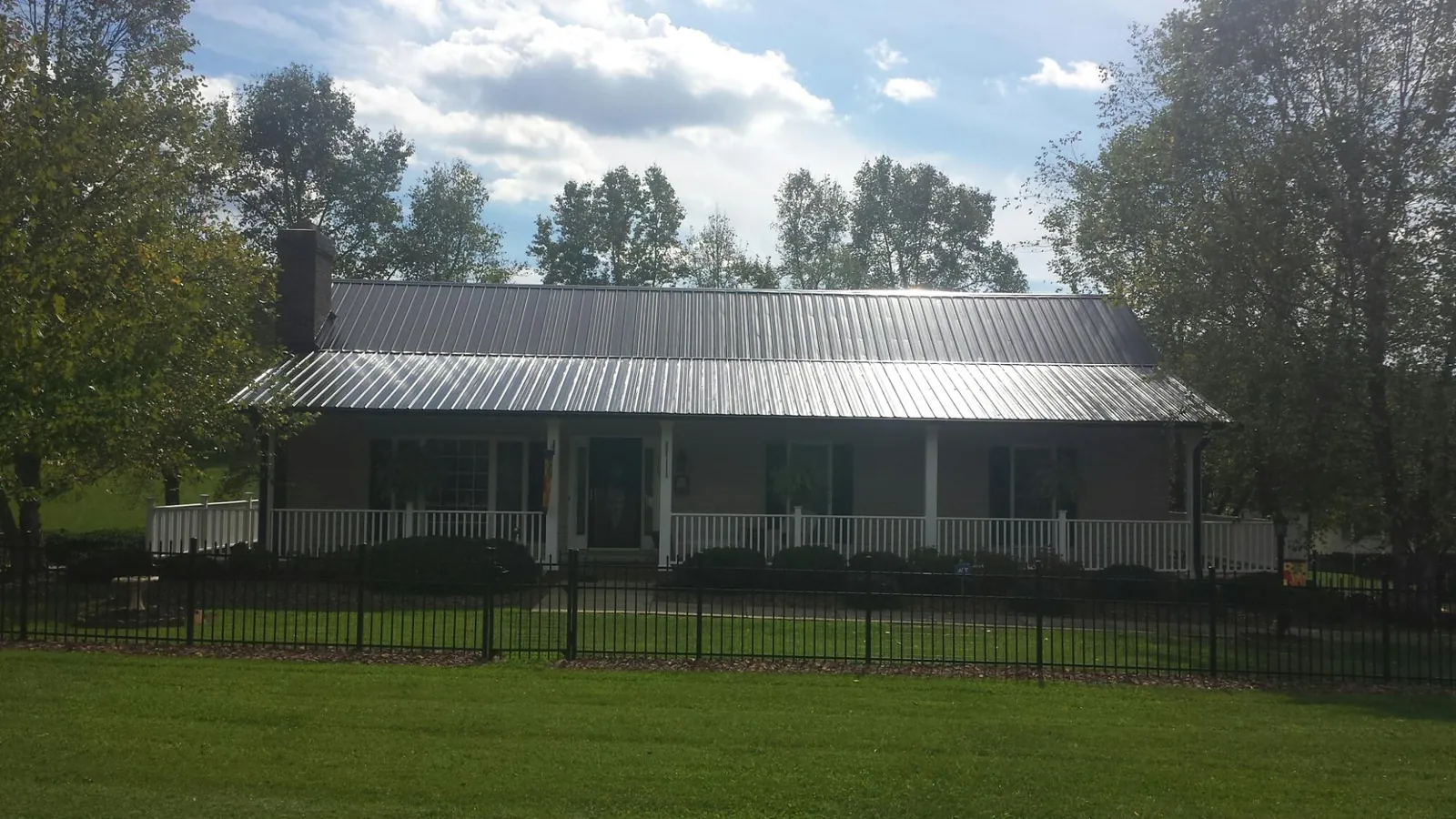 Gray metal roof on a brick ranch with a full width front porch — Gutter Guard Installation work by our crew in Rawlins