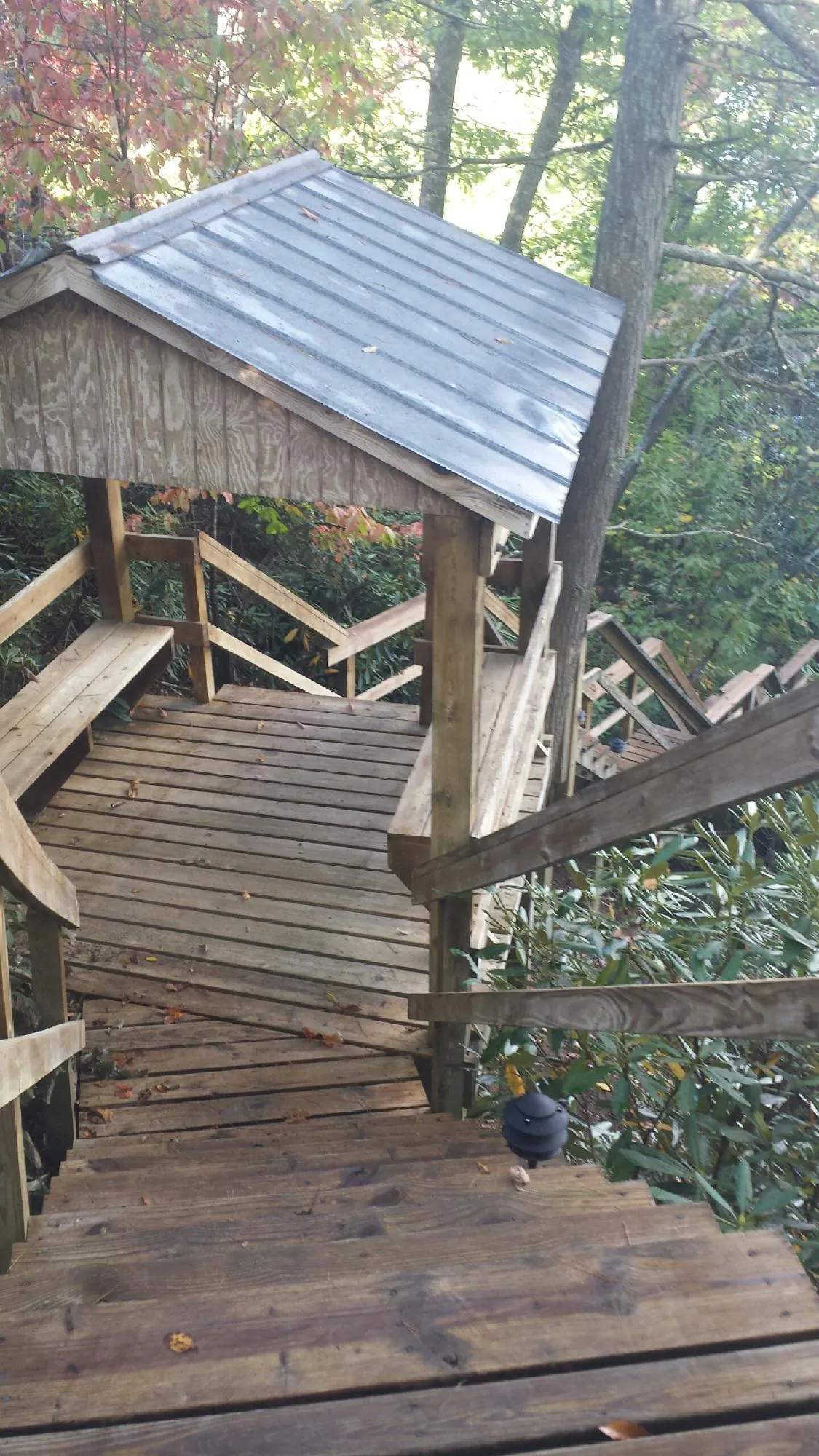 Metal roofed shelter over wooden steps on a wooded walkway — Skylight Repair & Installation work by our crew in Rawlins