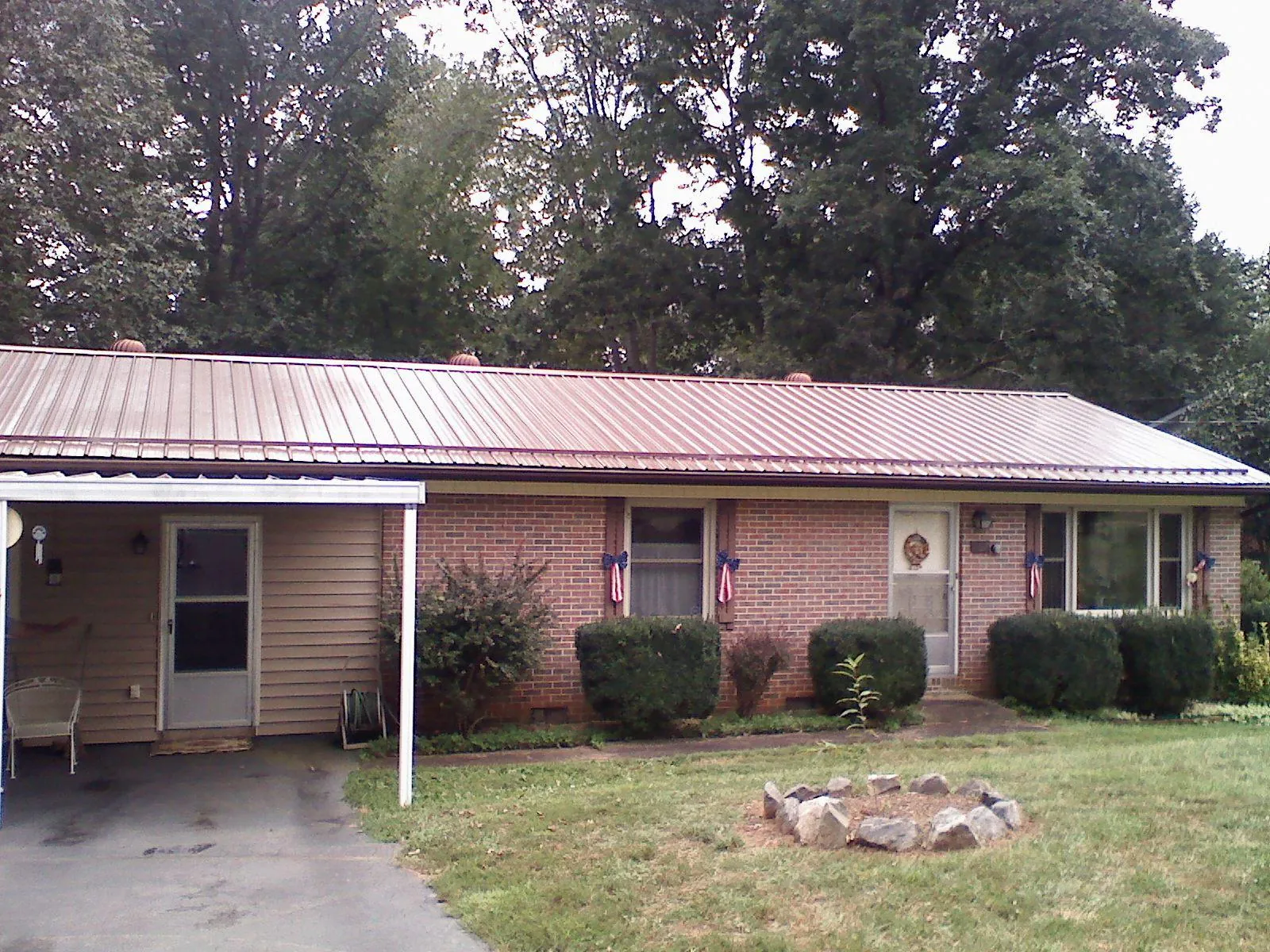 Bronze metal roof and carport on a brick ranch home — Roof Repair work by our crew in Rawlins