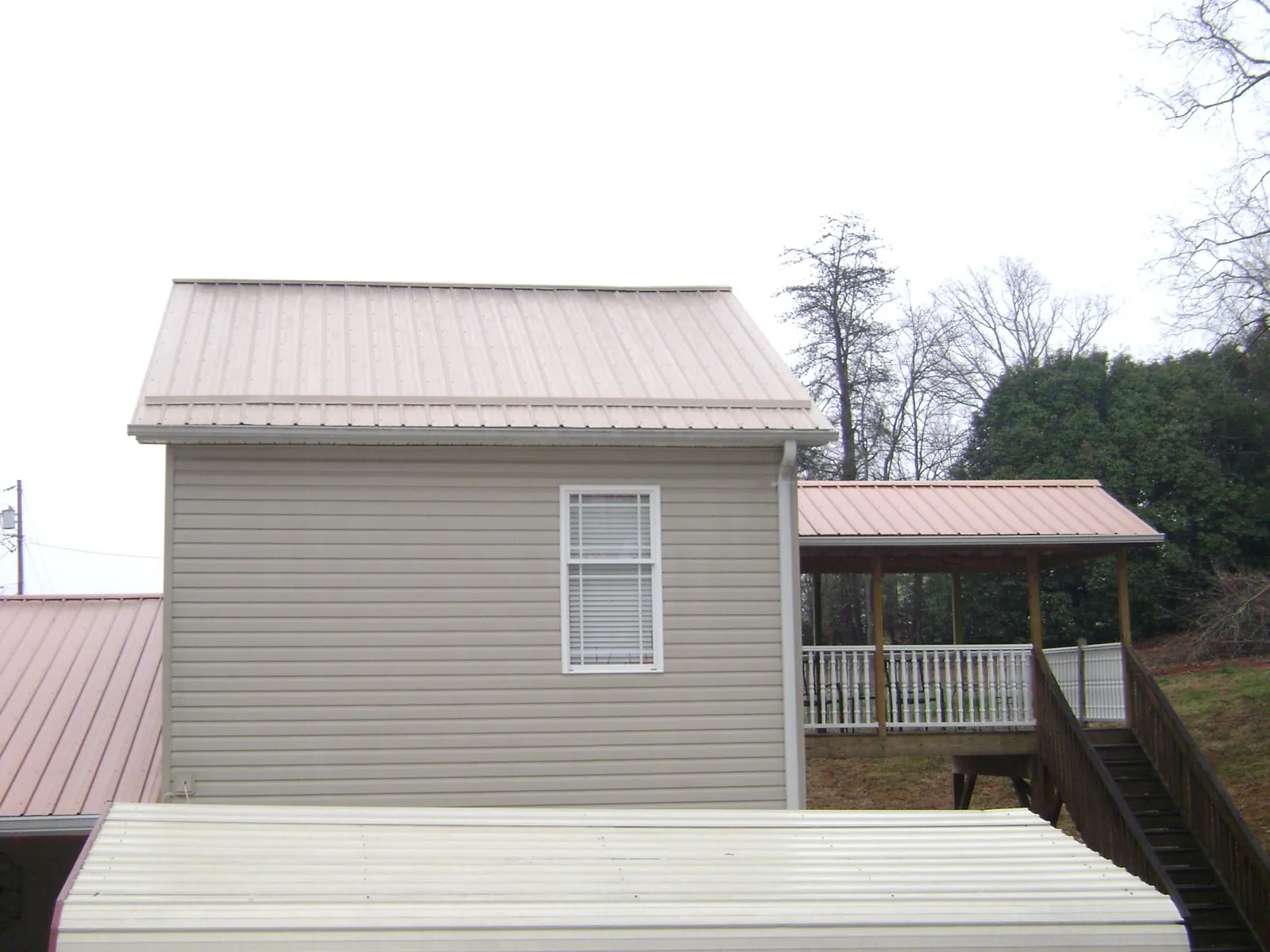 Tan metal roofs on a two story addition and attached porch, from a Roof Replacement job in Rawlins