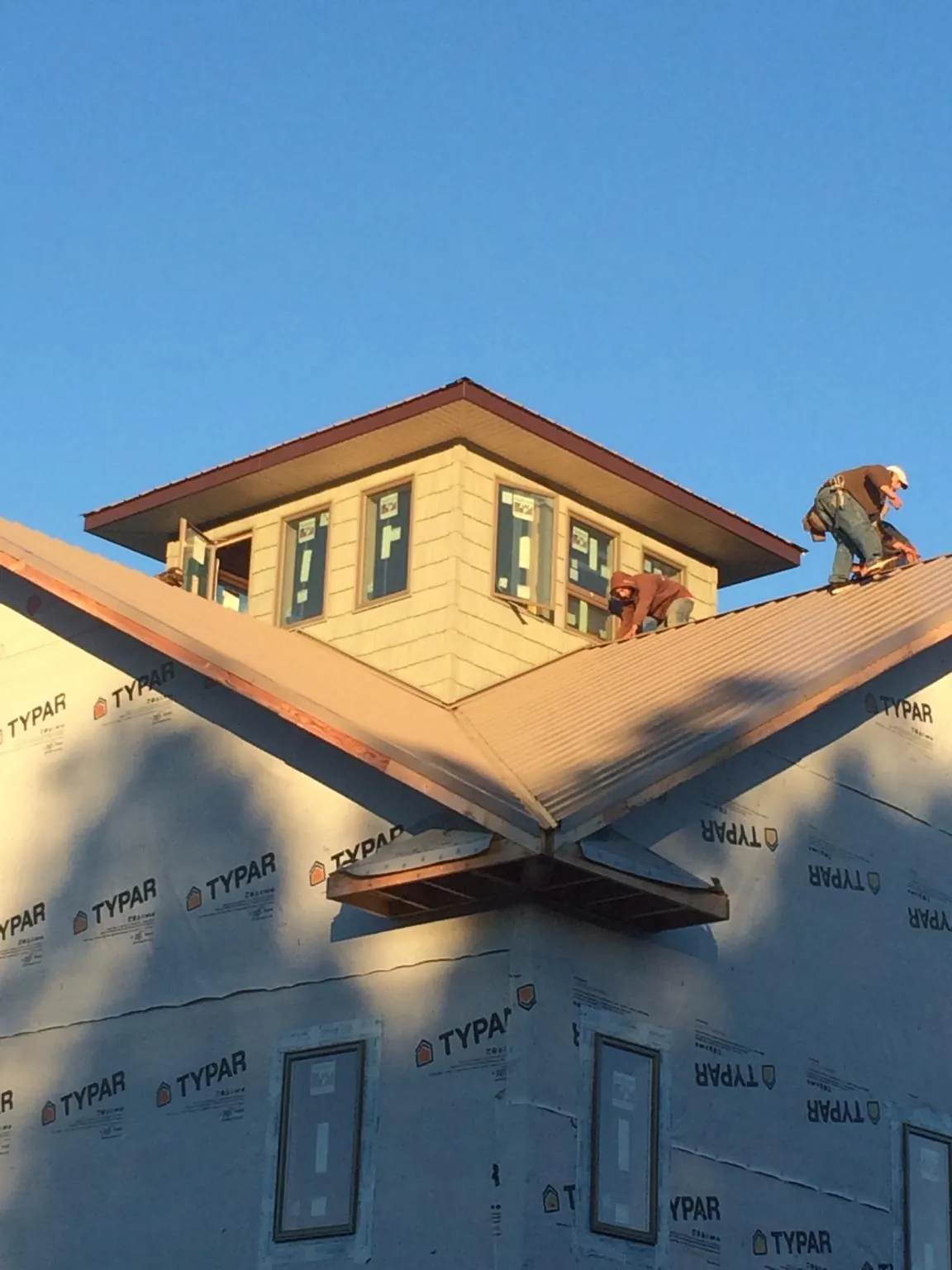 Roofers working around a rooftop cupola on a new metal roof at sunset — Roof Waterproofing in Rawlins by Roofing Brothers